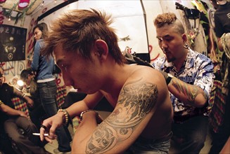 A man marks a tatto on a man's back