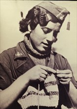 Jeune femme en uniforme militaire tricotant