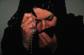 A catholic woman grieving and saying the rosary