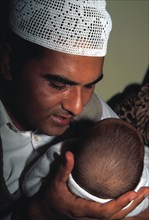 A Muslim father whispers the shahada in his new baby`s ear