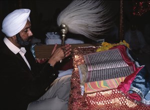 A Sikh member of the temple congregation fanning the Guru Granth Sahib with the chouri