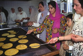 Volunteers from the temple congregation cooking chapattis for langar after prayers.