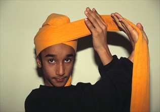 Un jeune Sikh enroule le turban traditionnel porté par tous les hommes Sikhs
