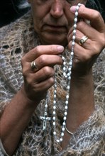 Rosary beads, a woman saying the rosary