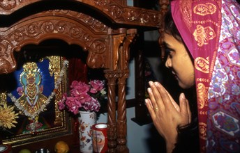 Woman praying before a small 'mandir' in a Hindu temple in the UK