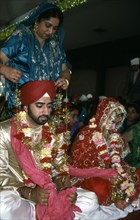 A mother garlands the groom for his wedding, India