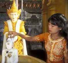 Purifying statue of the Buddha on the occasion of Wesak, woman in the Shwedagon Pagoda in Yangon,