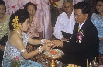 Khymer bride places ring on new husband`s finger Cambodian wedding ceremony