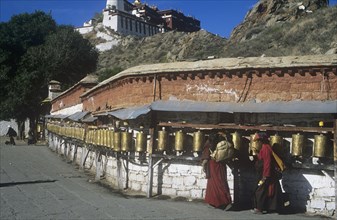 Pilgrims spin prayer-wheels with Potala Palace to rear Lhasa Tibet