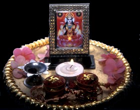 Puja tray with candle flowers and picture of Lakshmi