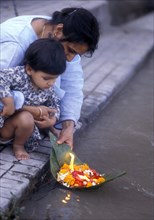 Child setting a lighted boat on the Ganges at Divali in India