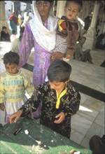 Mother teaching her son the meaning of giving in a mosque in Lahore