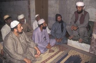 Imam of a small mosque in Lahore talking to the congregation of men
