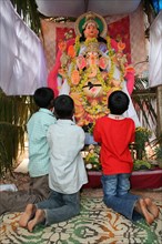 Boys worship in front of Ganesh the Hindu god with the trunk of an elephant