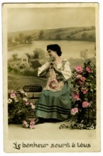 Carte postale représentant une femme posant parmi des fleurs