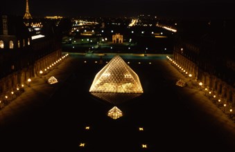 Vue des toits du Louvre de nuit, sur la Cour Napoléon et la Pyramide du Louvre / Au loin les