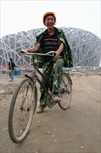 Cycliste chinois posant devant le stade "Nid d'oiseau" à Pékin