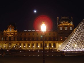 Facade and pyramid of the Louvre museum in Paris at night