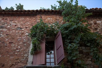Provence506 Provence, Luberon, village de Roussillon, mur, fenêtre, volets rouges, vigne vierge,