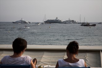 CoteAzur022 Cannes, la Croisette, les plages et la baie, yachts, deux femmes assises face à la baie