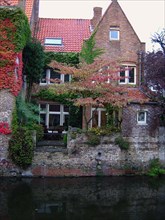 Bruges. Maison au bord du canal en automne, vigne vierge