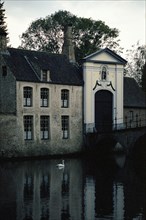 Bruges. Façade de l'entrée du Béguinage (Begijnhof) 1776 sur le canal, en automne à la tombée du