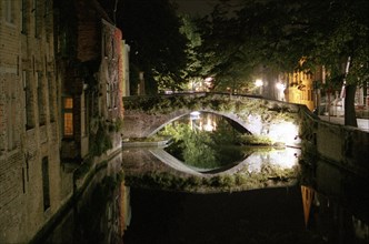 Bruges de nuit : maisons sur le canal, pont et quai, reflets dans le canal, en automne