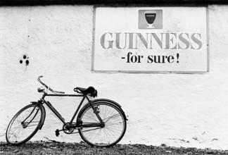 Bicyclette contre le mur d'un pub, sous une publicité pour la bière Guinness.
Comté de Kildare,