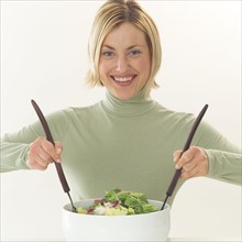 Young woman mixing a salad.