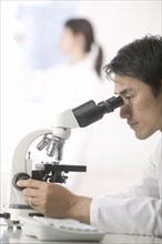 Scientist looking in microscope.