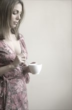 Profile of woman stirring coffee.