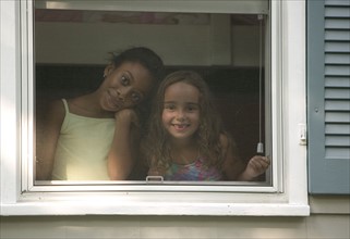 Two girls looking out a window.