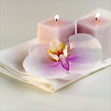 Lighted candles with a colorful orchid.