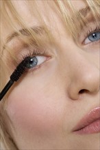 Woman's face with mascara brush.
