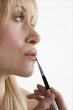 Profile of woman applying lipstick.