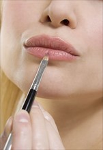 Woman's lips with lipstick brush.