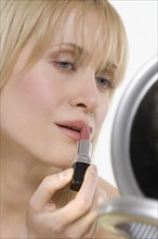 Woman with mirror applying lipstick.