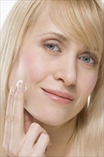 Headshot of woman applying face cream.