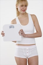 Smiling woman holding scale.