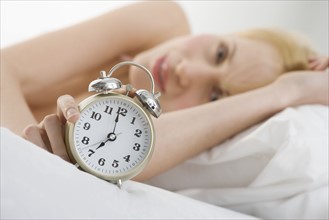 Woman holding alarm clock.