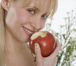 Smiling woman eating apple.