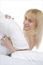 Woman playing with pillow in bed.