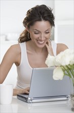 Smiling woman with laptop and cup.