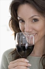 Smiling woman drinking red wine.