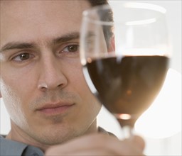 Man inspecting glass of red wine.