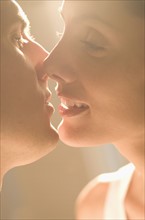 Closeup of couple kissing in sunlight.