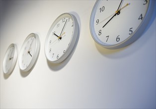 Closeup of clocks telling different times.