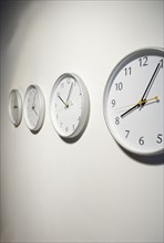 Row of clocks hanging on wall.