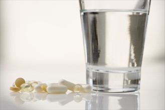 Pile of pills with water glass.