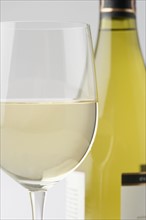Glass of white wine with bottle.
